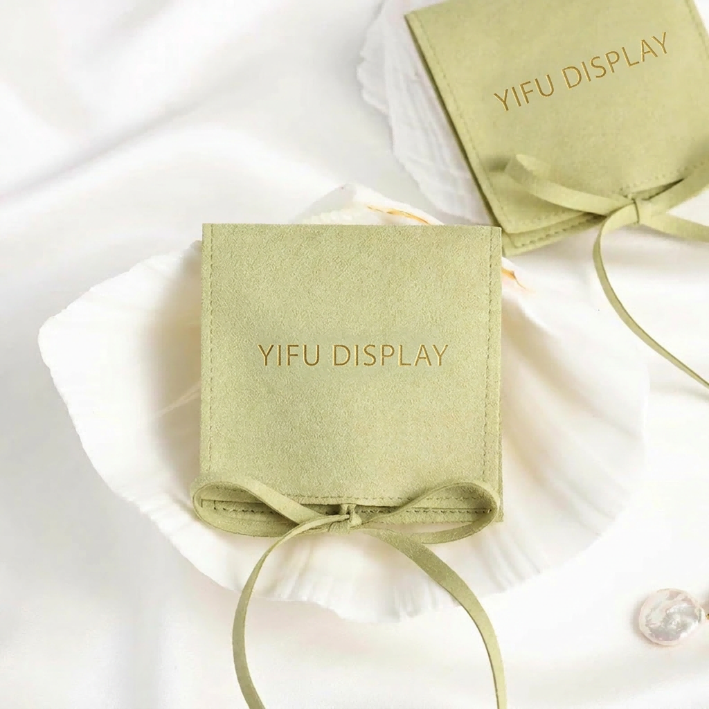 Custom drawstring jewelry pouch with embossed gold logo for rings and necklaces packaging.