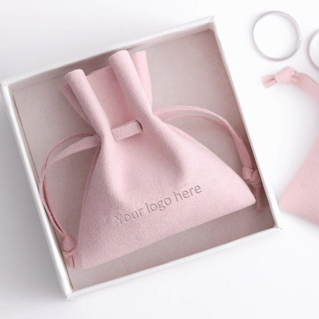 Pink microfiber jewelry pouch with debossed logo for luxury brand identity, high-quality drawstring packaging.